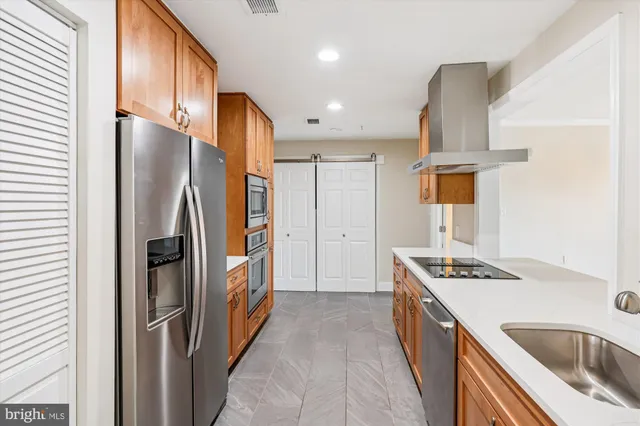a kitchen with stainless steel appliances granite countertop a refrigerator a sink and wooden cabinets