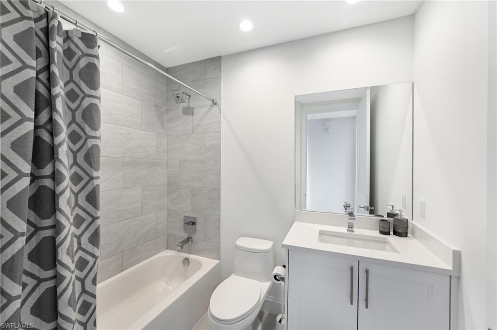 1111 Central, Unit 417S Naples, FL 34104 - Photo 16 of 25 a bathroom with a granite countertop sink toilet a mirror a bathtub and shower