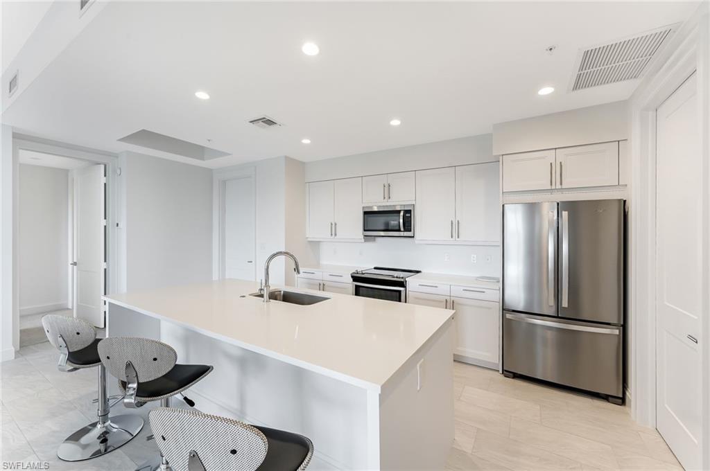 1111 Central, Unit 417S Naples, FL 34104 - Photo 9 of 25 a kitchen with stainless steel appliances a sink a stove a refrigerator and cabinets
