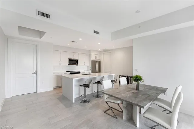 a kitchen with stainless steel appliances a white stove top oven a sink a refrigerator with white cabinets and wooden floor