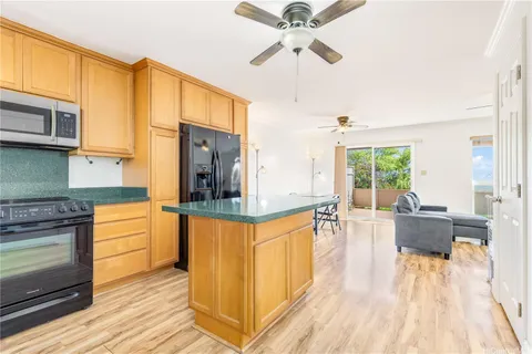 a living room with stainless steel appliances granite countertop furniture a fireplace a flat screen tv and a large window