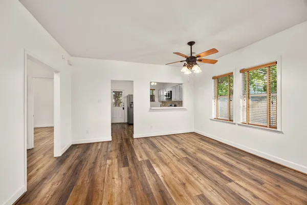 a view of an empty room with window and wooden floor