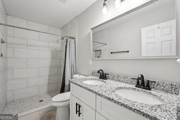 a bathroom with a granite countertop sink a toilet and shower