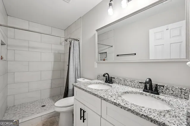 a bathroom with a granite countertop sink a toilet and shower