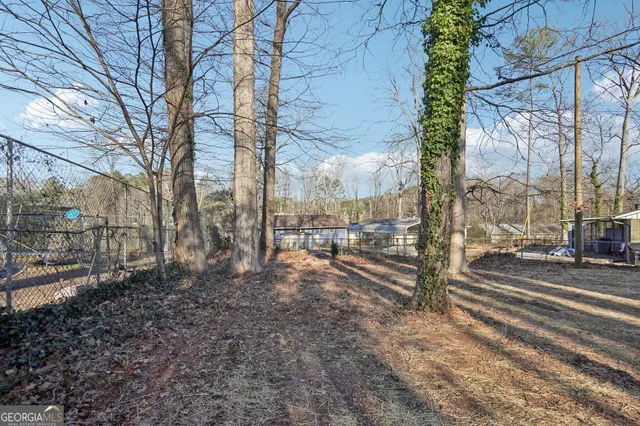 a backyard of a house with large trees and wooden fence
