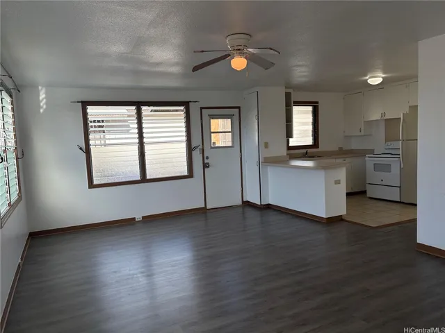 an empty room with wooden floor cabinet and windows