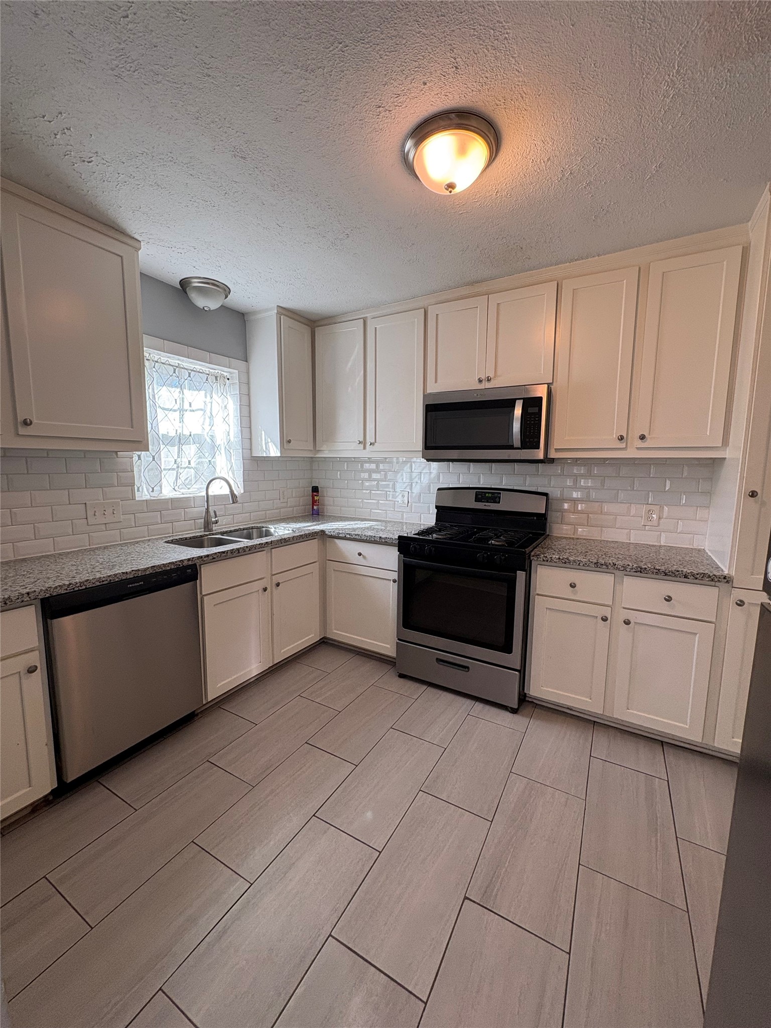 943 West 43rd Street Houston, TX 77018 - Photo 6 of 10 a kitchen with granite countertop a stove sink and cabinets