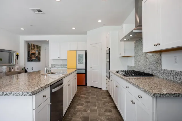 a kitchen with granite countertop kitchen island stainless steel appliances a sink stove and cabinets