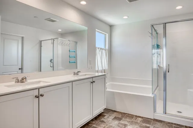 a bathroom with a tub sink double vanity and mirror