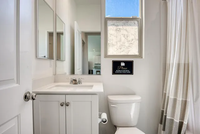 a bathroom with a toilet a sink a mirror and a window