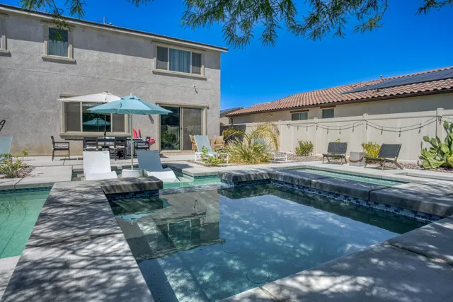 a view of a patio with couches table and chairs with potted plants and large tree
