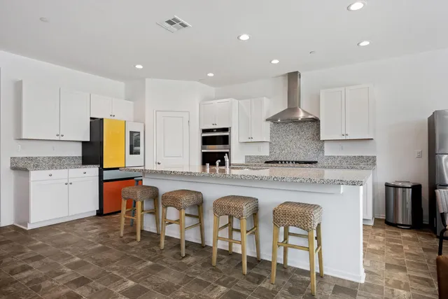 a large kitchen with cabinets chairs and refrigerator
