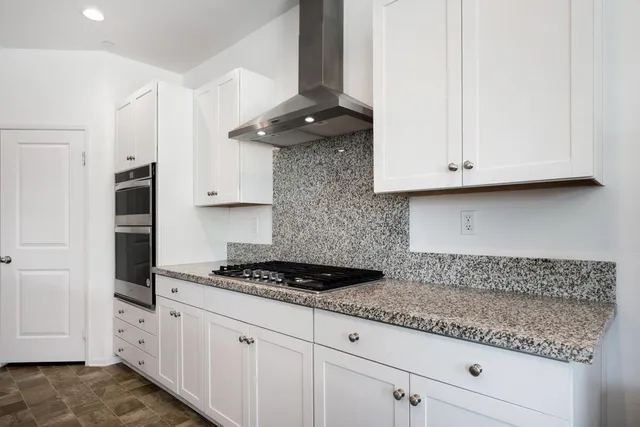 a kitchen with stainless steel appliances granite countertop white cabinets and a stove