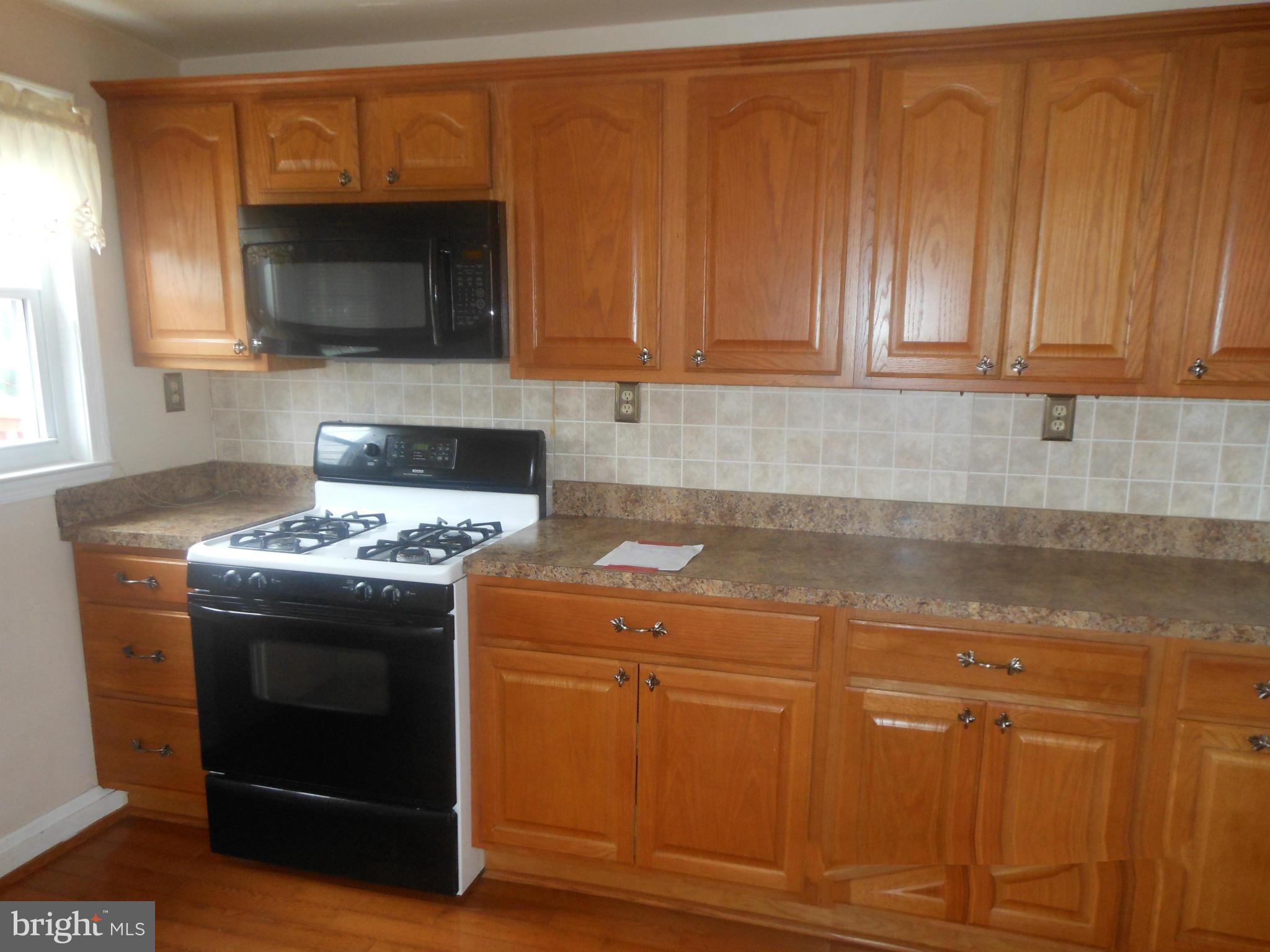 1413 Barrett Road Baltimore, MD 21207 - Photo 6 of 13 a kitchen with granite countertop a stove and a microwave