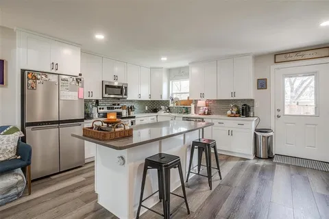a kitchen with kitchen island white cabinets appliances and wooden floor