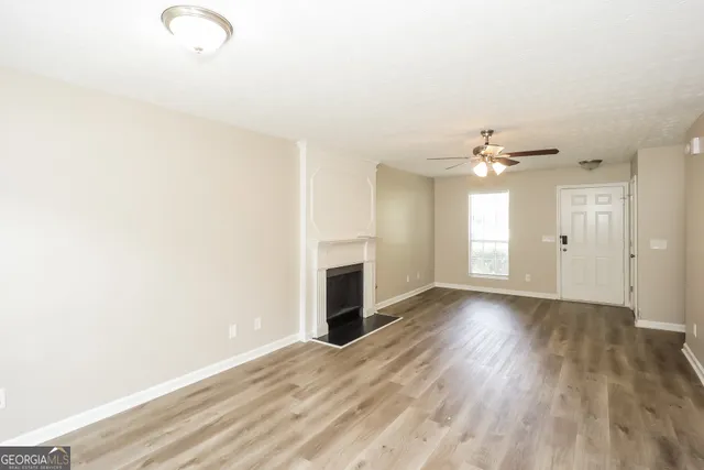 an empty room with wooden floor fireplace and windows