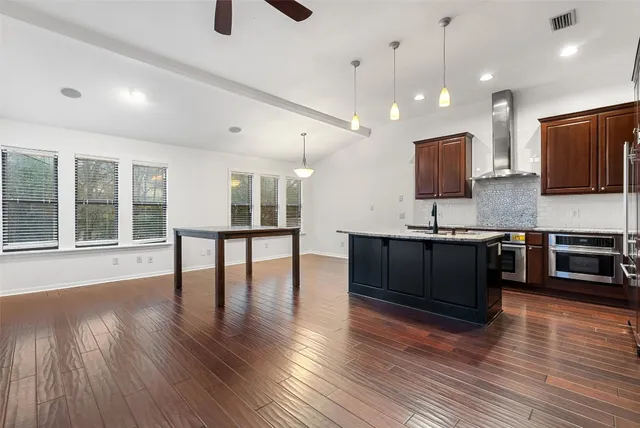 a living room with stainless steel appliances kitchen island granite countertop wooden floors and a sink