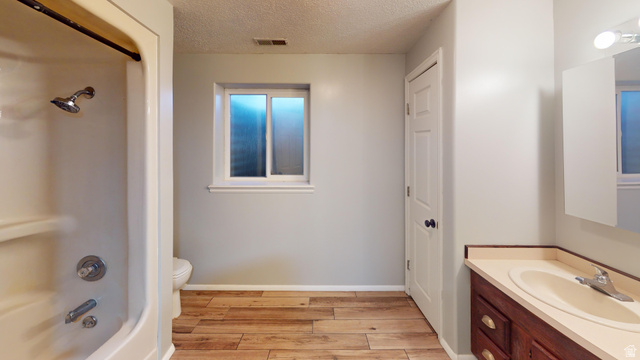 9029 North Treasureton Road Preston, ID 83263 - Photo 19 of 31 Bathroom with vanity, bathing tub / shower combination, a textured ceiling, and light wood-style flooring