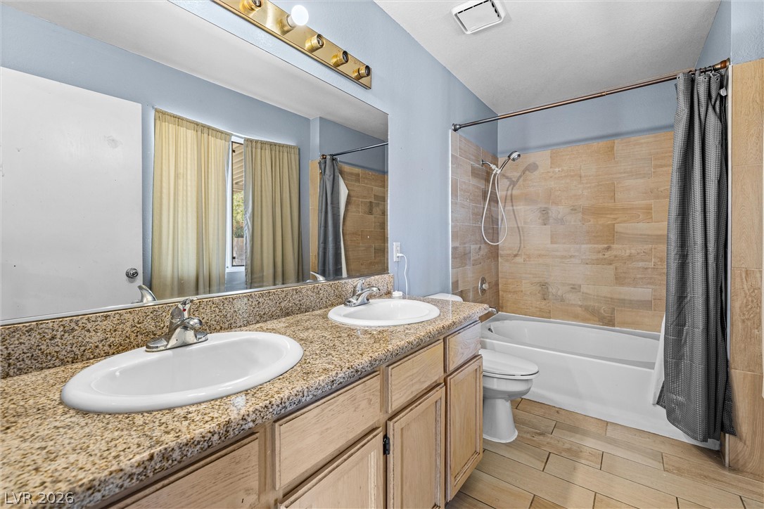 1624 Palmae Way Las Vegas, NV 89128 - Photo 10 of 18 This bathroom features a double vanity with granite counters and a shower-tub combination with wood-look tile.