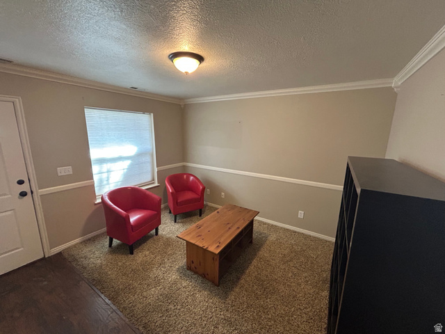 432 Spring Lane Logan, UT 84341 - Photo 4 of 22 Sitting room featuring a textured ceiling, crown molding, and dark carpet