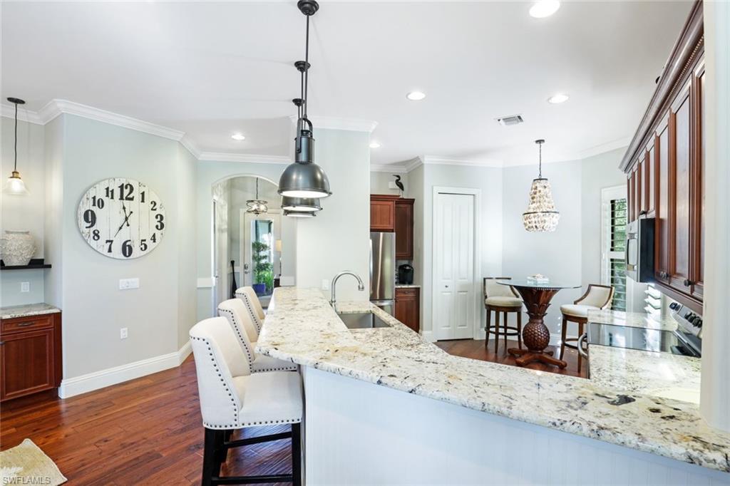 7599 Moorgate Point Way Naples, FL 34113 - Photo 5 of 38 a dining room with wooden floor a chandelier a wooden table and chairs