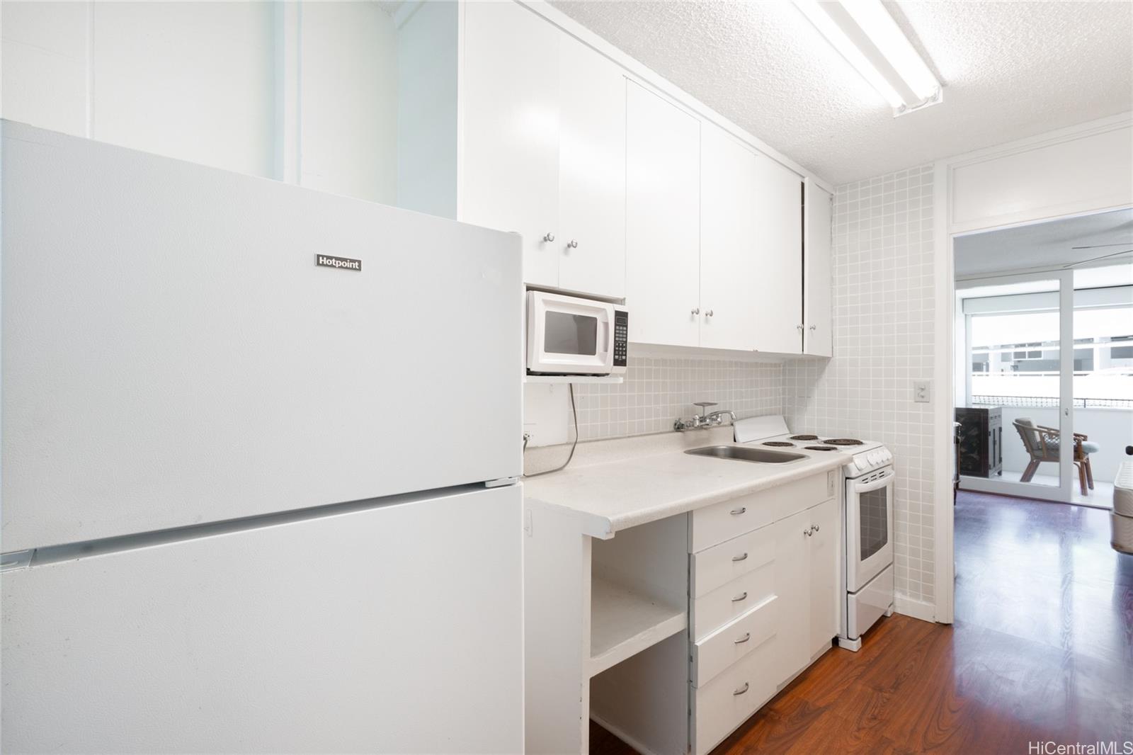 425 Ena Road, Unit 308C Honolulu, HI 96815 - Photo 3 of 10 a kitchen with a sink a stove a refrigerator and white cabinets