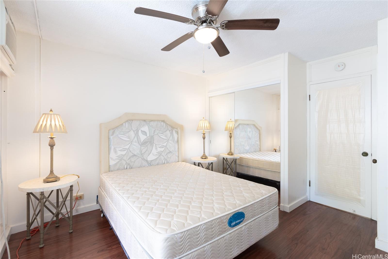 425 Ena Road, Unit 308C Honolulu, HI 96815 - Photo 6 of 10 a bedroom with a bed and a chandelier