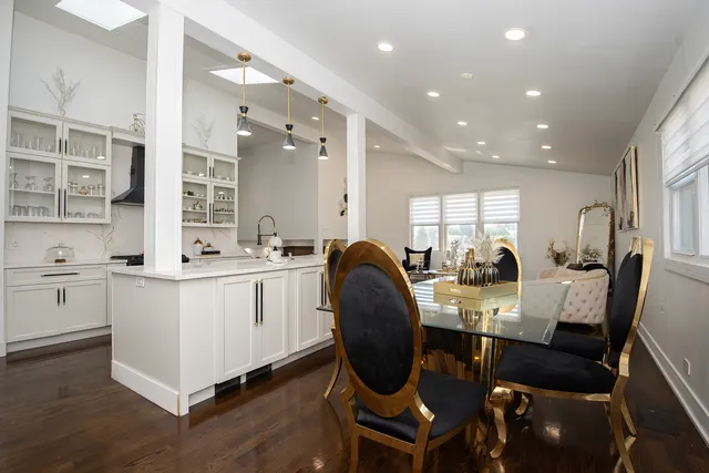 a very nice looking open dining room with kitchen island furniture a wooden floor and a sink