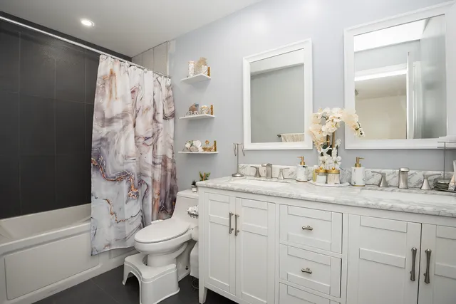 a bathroom with a granite countertop sink toilet a mirror a bathtub and shower
