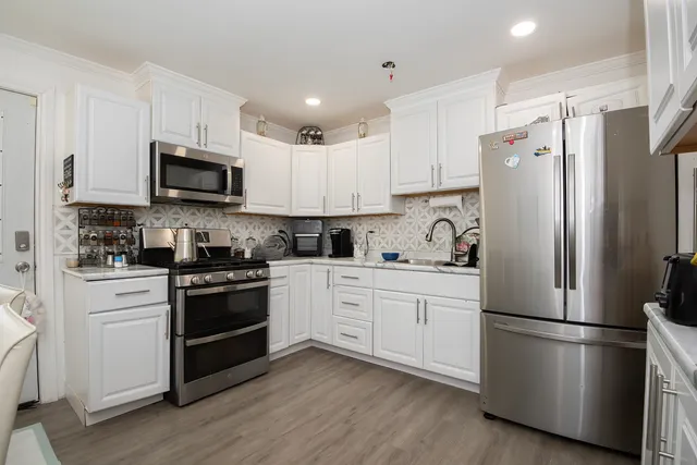 a kitchen with granite countertop white cabinets and stainless steel appliances