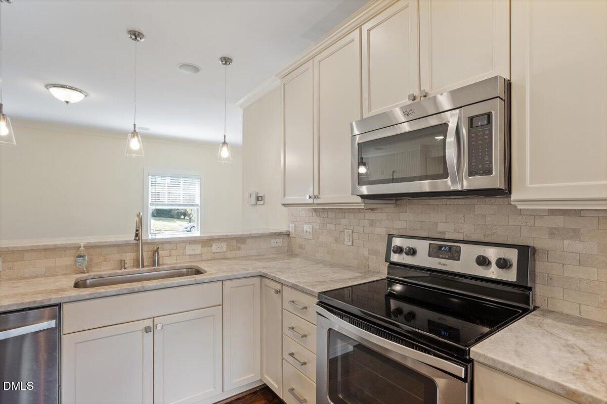 2718 Peachtree Street Raleigh, NC 27608 - Photo 16 of 38 a kitchen with cabinets stainless steel appliances and a sink