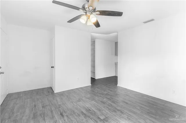 an empty room with wooden floor chandelier fan and closet in a room