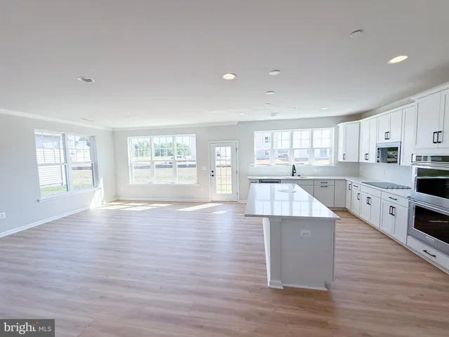 a large kitchen with stainless steel appliances granite countertop a large counter top and a wooden floors