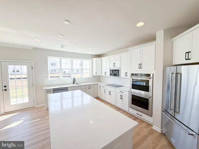 a large white kitchen with a refrigerator a stove a sink and a window