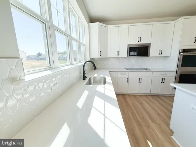 a large white kitchen with wooden floor and a window