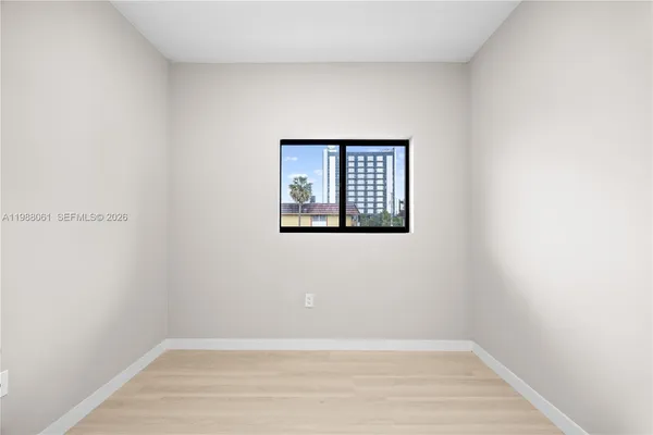 a view of an empty room with wooden floor and a window