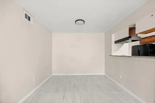 a view of a refrigerator in kitchen and an empty room