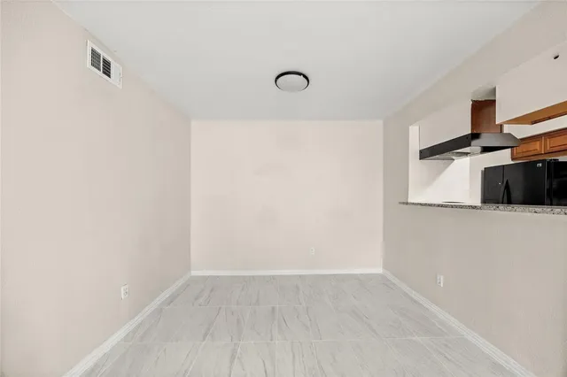 a view of a refrigerator in kitchen and an empty room