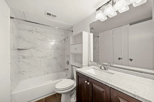 a bathroom with a sink a toilet a mirror a bathtub and shower