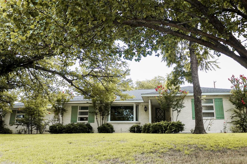a front view of a house with garden and trees