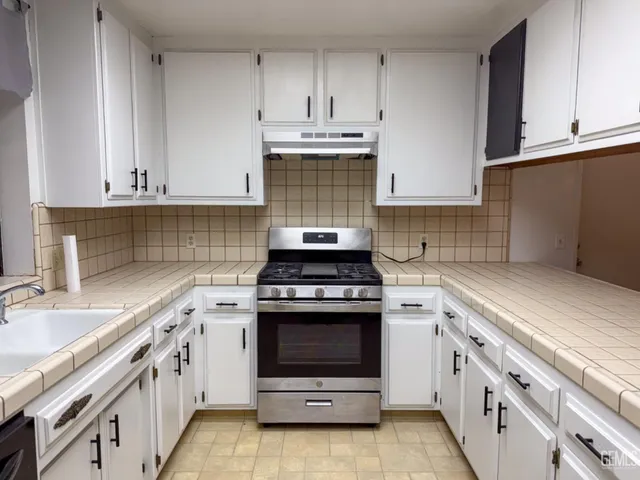 a kitchen with stainless steel appliances white cabinets and a stove top oven