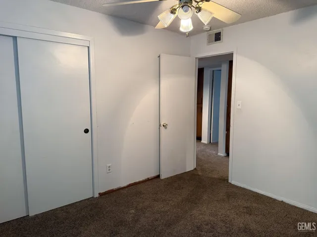 a view of an empty room with a chandelier fan