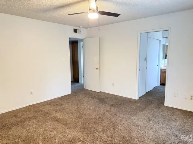 an empty room with closet and a ceiling fan