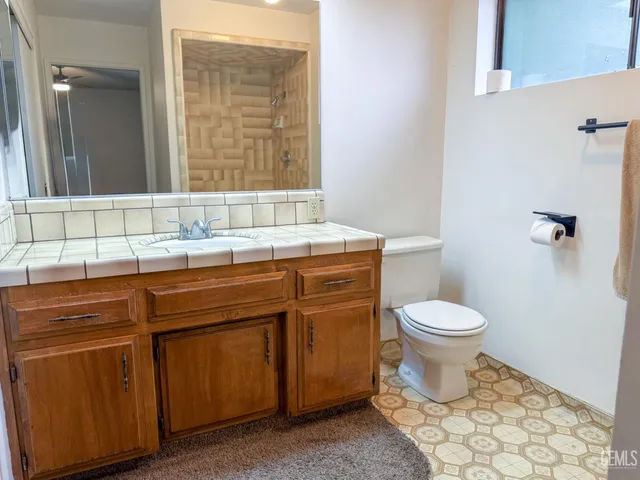 a bathroom with a granite countertop toilet sink and mirror