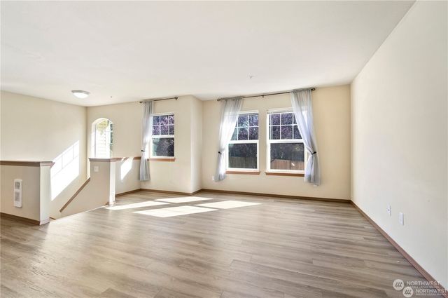 a view of a big room with wooden floor and windows