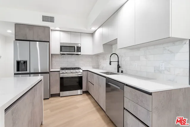 a kitchen with stainless steel appliances a sink stove and refrigerator