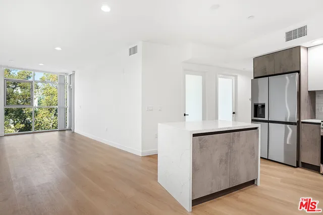a kitchen with stainless steel appliances a refrigerator and a more cabinets