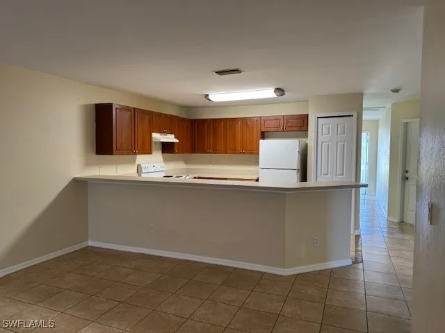 a kitchen with granite countertop a refrigerator and a stove top oven