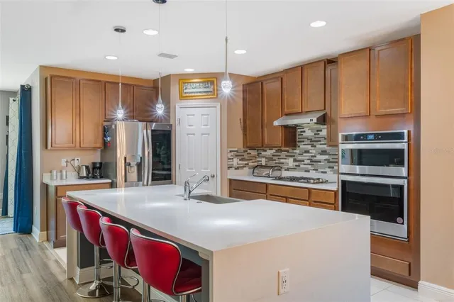a kitchen with stainless steel appliances kitchen island granite countertop a table chairs and a refrigerator