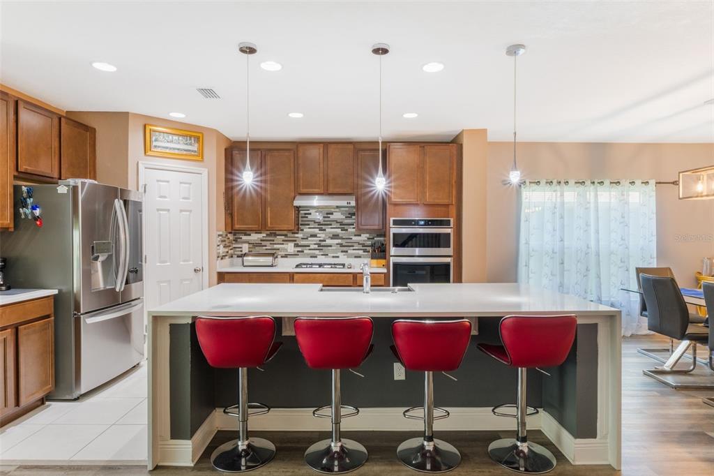 1108 Cavender Creek Road Minneola, FL 34715 - Photo 19 of 54 a kitchen with stainless steel appliances kitchen island granite countertop a table chairs and a refrigerator